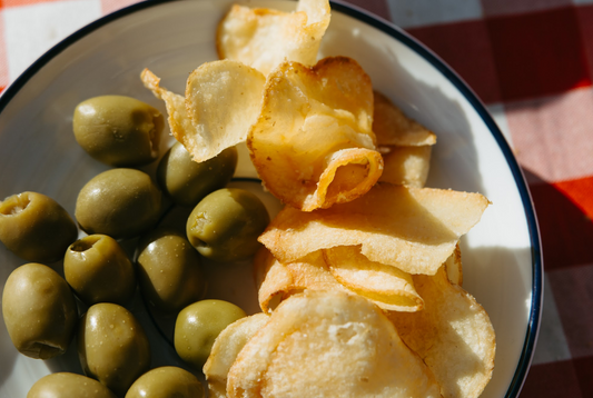 Made in USA potato chips displayed on a serving bowl with olives on a picnic table.